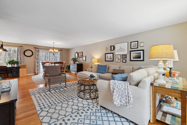 living area featuring an inviting chandelier, light wood-style flooring, and baseboards