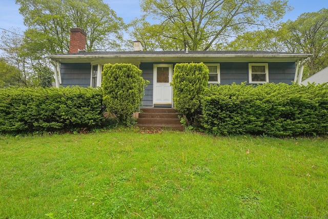 view of front facade featuring a chimney, entry steps, and a front yard