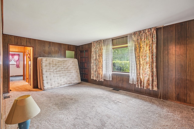 unfurnished living room featuring wood walls, plenty of natural light, and visible vents