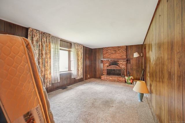 unfurnished living room featuring carpet flooring, wood walls, visible vents, and a brick fireplace