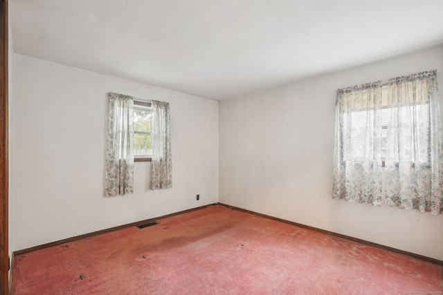 empty room with baseboards, visible vents, and carpet