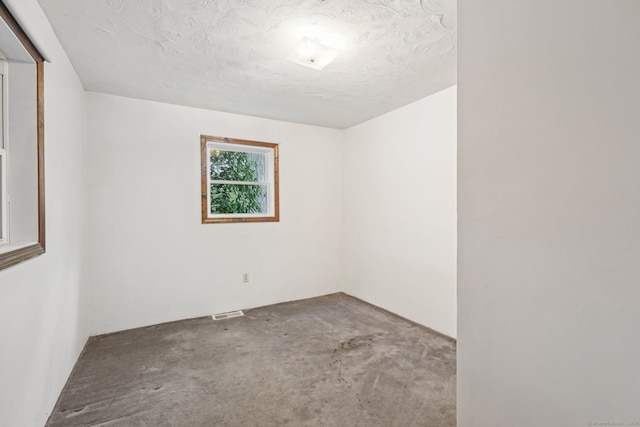 empty room with carpet flooring, visible vents, and a textured ceiling