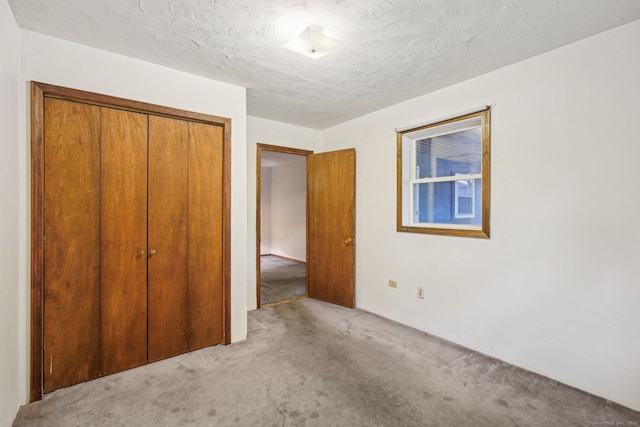 unfurnished bedroom with a textured ceiling, carpet flooring, and a closet