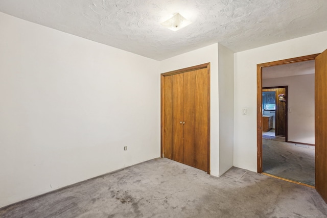 unfurnished bedroom with a textured ceiling, a closet, and carpet