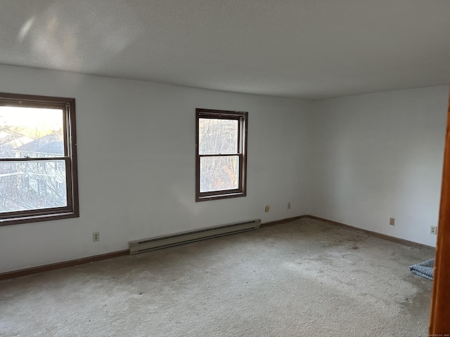 carpeted spare room with a wealth of natural light, a baseboard radiator, and baseboards