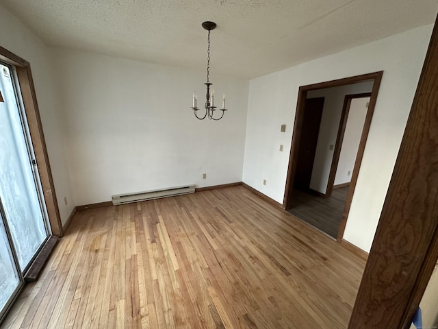 interior space with light wood-type flooring, baseboards, baseboard heating, and a notable chandelier