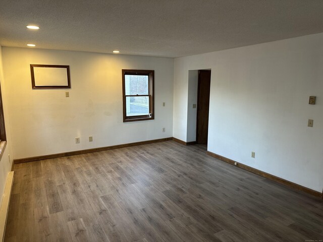 unfurnished room with recessed lighting, wood finished floors, and baseboards