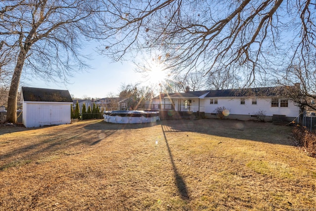 view of yard with a covered pool, a storage shed, fence, and an outdoor structure