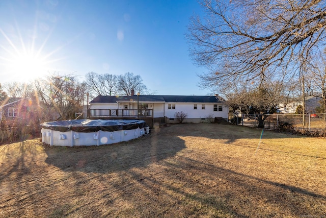 rear view of house featuring fence, driveway, a wooden deck, a covered pool, and crawl space