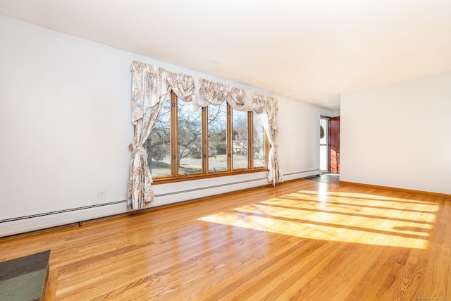 unfurnished living room with a baseboard radiator, baseboards, and wood finished floors