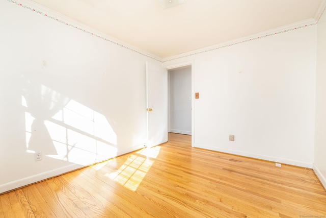 unfurnished room featuring crown molding, light wood-style flooring, and baseboards