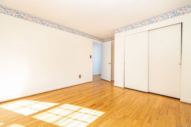 unfurnished bedroom featuring a closet, baseboards, and light wood finished floors