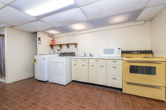 kitchen with washer and clothes dryer, white appliances, a paneled ceiling, and open shelves