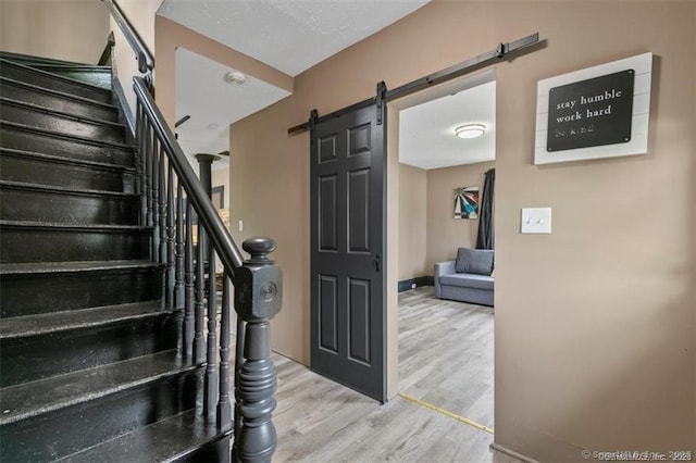 stairs with wood finished floors, baseboards, and a barn door