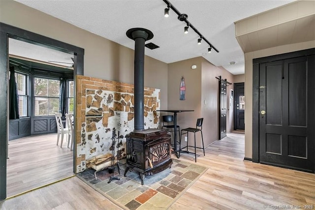 interior space featuring light wood finished floors, a barn door, a textured ceiling, and a wood stove