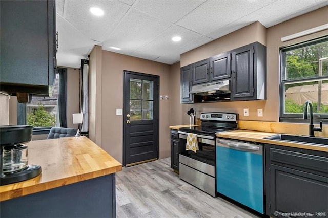 kitchen featuring dishwashing machine, butcher block counters, stainless steel range with electric stovetop, and under cabinet range hood