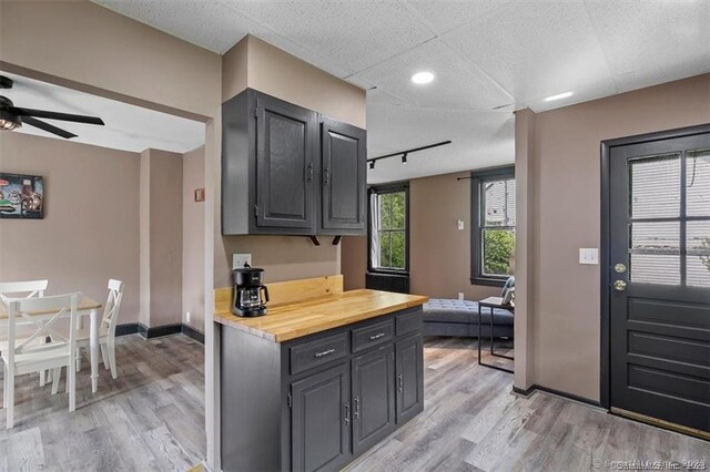 kitchen with light wood-style floors, butcher block countertops, ceiling fan, and baseboards