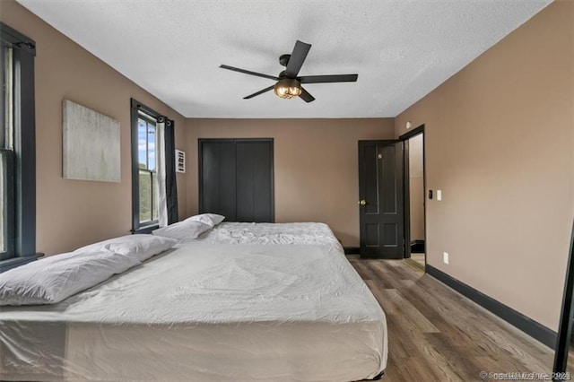 bedroom featuring a textured ceiling, ceiling fan, dark wood-style flooring, and baseboards