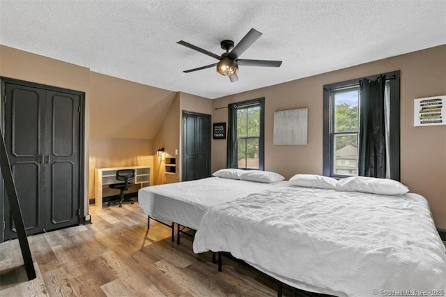 bedroom featuring light wood-style floors, a ceiling fan, and a textured ceiling