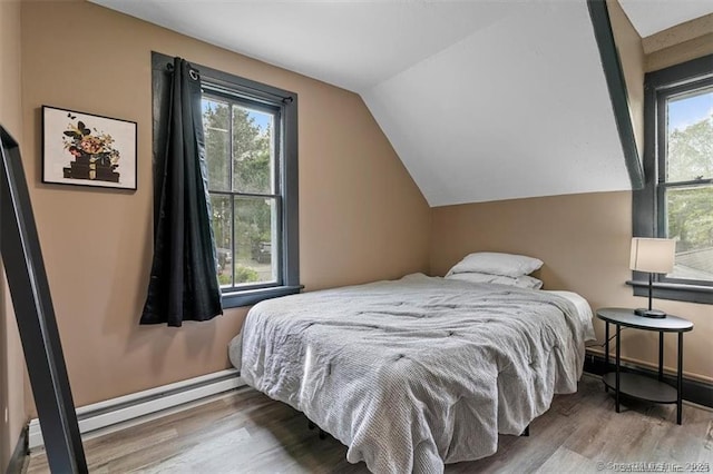 bedroom with multiple windows, vaulted ceiling, and wood finished floors