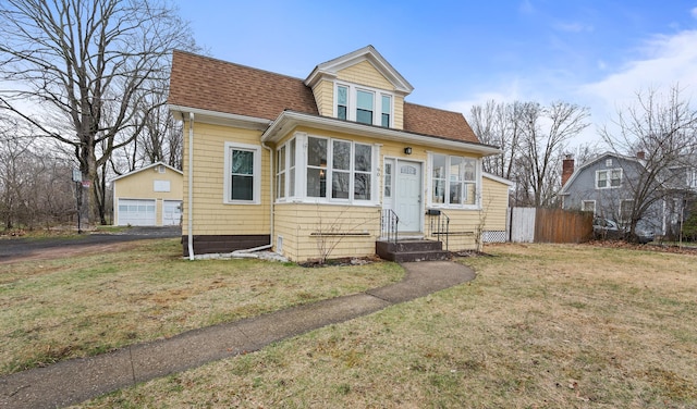 bungalow-style house featuring an outbuilding, entry steps, a front lawn, and a shingled roof
