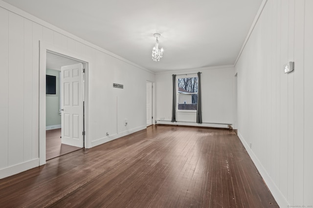 spare room with crown molding, an inviting chandelier, hardwood / wood-style floors, a baseboard radiator, and baseboards
