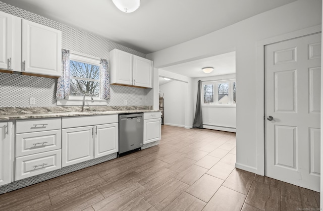 kitchen with decorative backsplash, a baseboard heating unit, dishwasher, and white cabinets