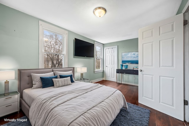 bedroom with a closet, baseboards, multiple windows, and wood finished floors