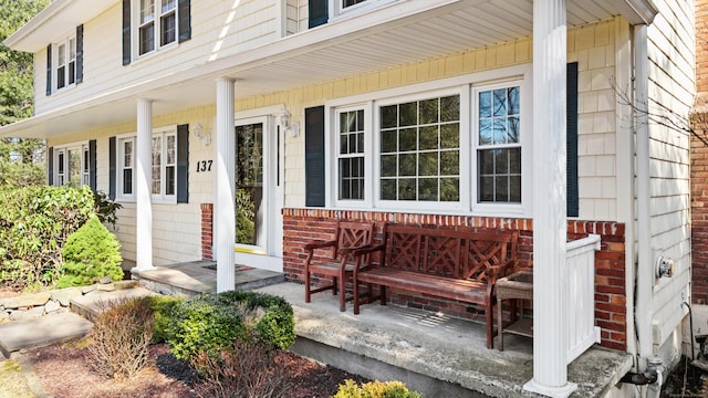 entrance to property with brick siding and a porch