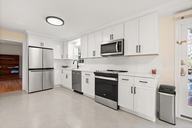 kitchen with a sink, stainless steel appliances, white cabinets, light countertops, and decorative backsplash