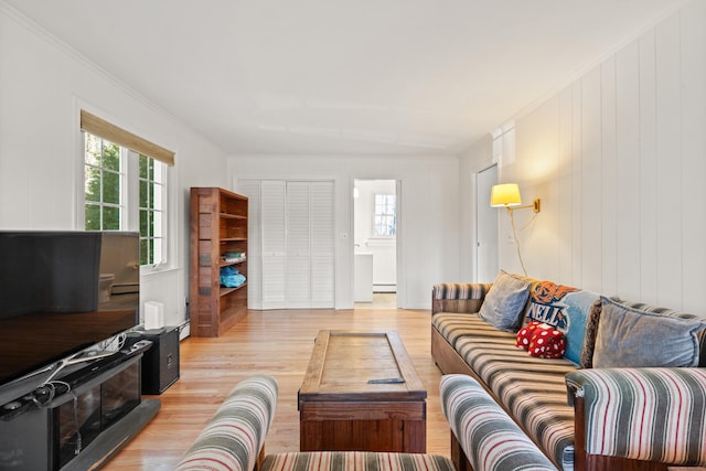 living room with light wood-type flooring, baseboard heating, and ornamental molding