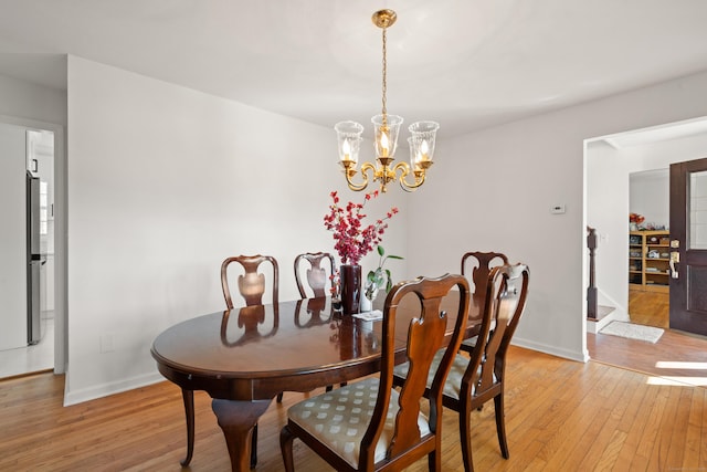 dining area with baseboards, light wood-style floors, and an inviting chandelier