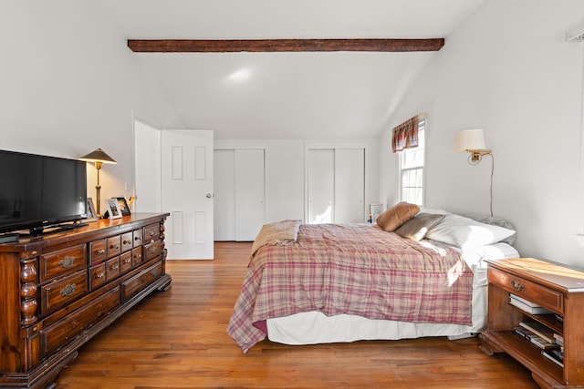 bedroom with lofted ceiling with beams, multiple closets, and wood finished floors