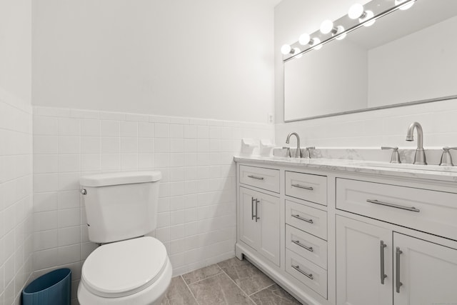 bathroom with double vanity, toilet, tile walls, and a sink