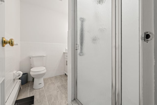 bathroom featuring a wainscoted wall, a shower stall, a baseboard heating unit, tile walls, and toilet