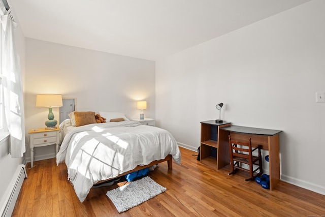 bedroom featuring baseboards, baseboard heating, and wood finished floors