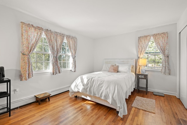 bedroom with baseboard heating, baseboards, and wood-type flooring