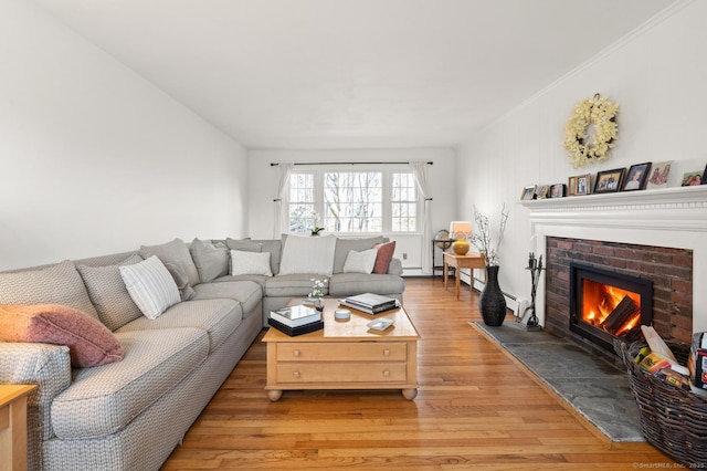 living room with light wood finished floors, a fireplace, and ornamental molding