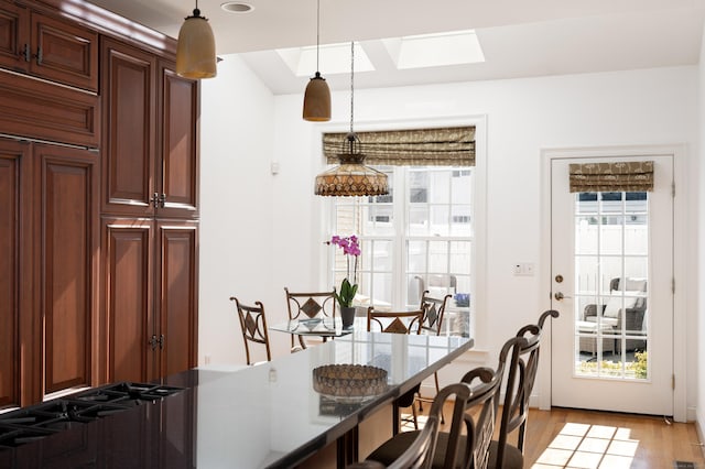 dining room with light wood-style flooring and a skylight