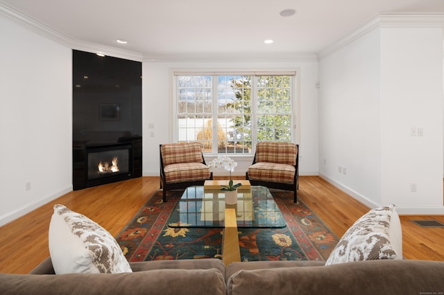 living room with visible vents, wood finished floors, and ornamental molding