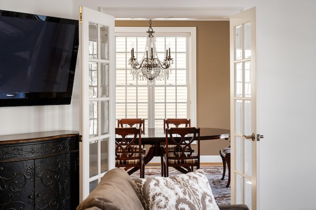 interior space featuring french doors, multiple windows, a chandelier, and crown molding