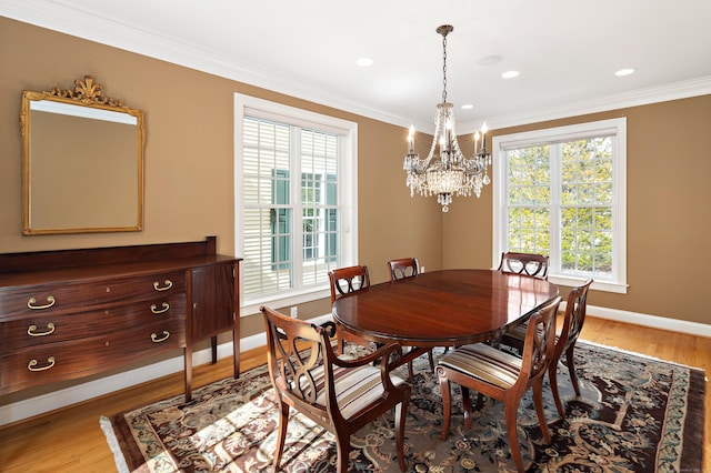 dining space featuring light wood-style flooring, a notable chandelier, a wealth of natural light, and ornamental molding