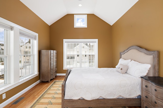 bedroom featuring visible vents, baseboards, lofted ceiling, and wood finished floors