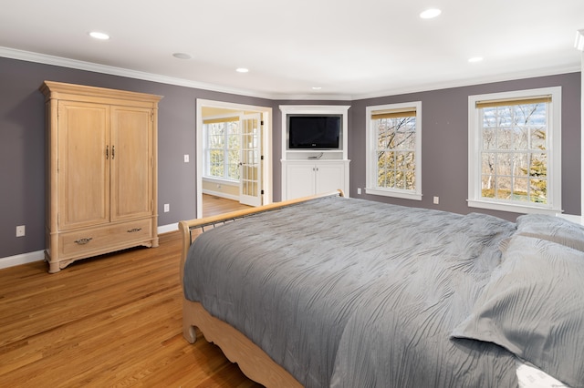 bedroom featuring multiple windows, crown molding, and light wood-style floors