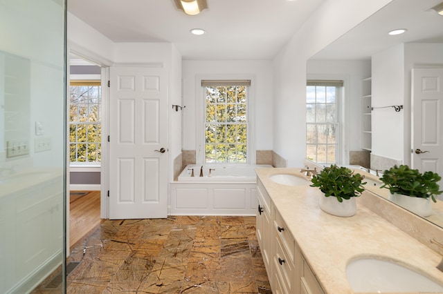 bathroom featuring a sink, a garden tub, and double vanity