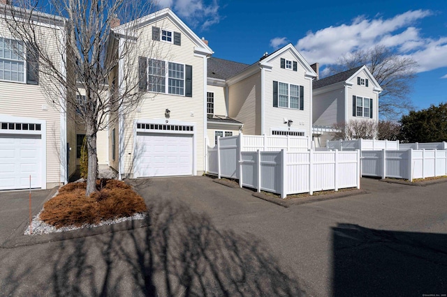 view of front of house featuring a garage, driveway, and fence