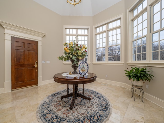 foyer entrance featuring baseboards and a chandelier