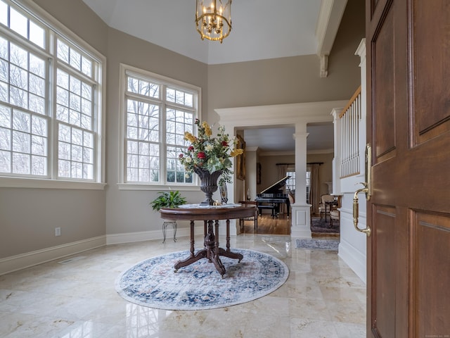 foyer featuring a notable chandelier, baseboards, marble finish floor, stairway, and ornate columns