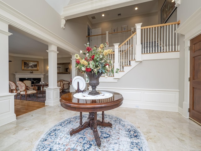 foyer entrance with a decorative wall, a wainscoted wall, stairs, decorative columns, and crown molding