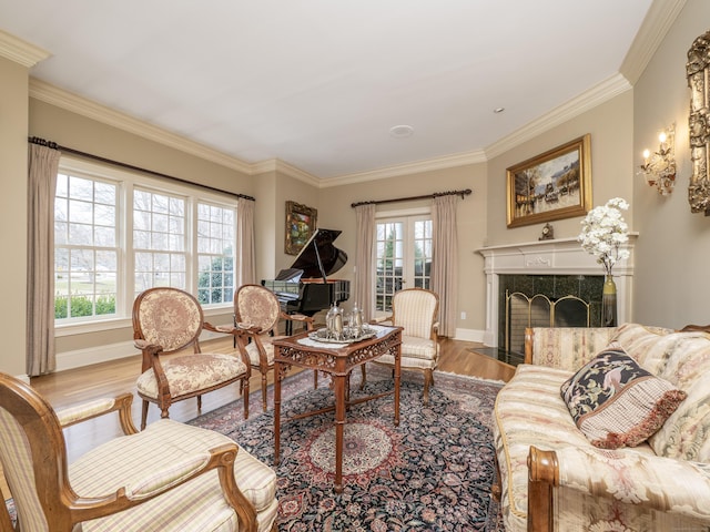 living room featuring crown molding, a fireplace, baseboards, and wood finished floors